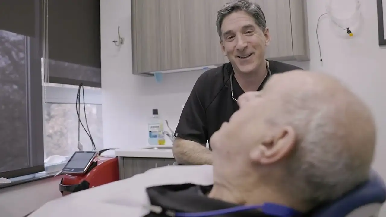Dr. Matthew Teich smiling with a patient in a treatment room at Westchester Dental Group, White Plains.
